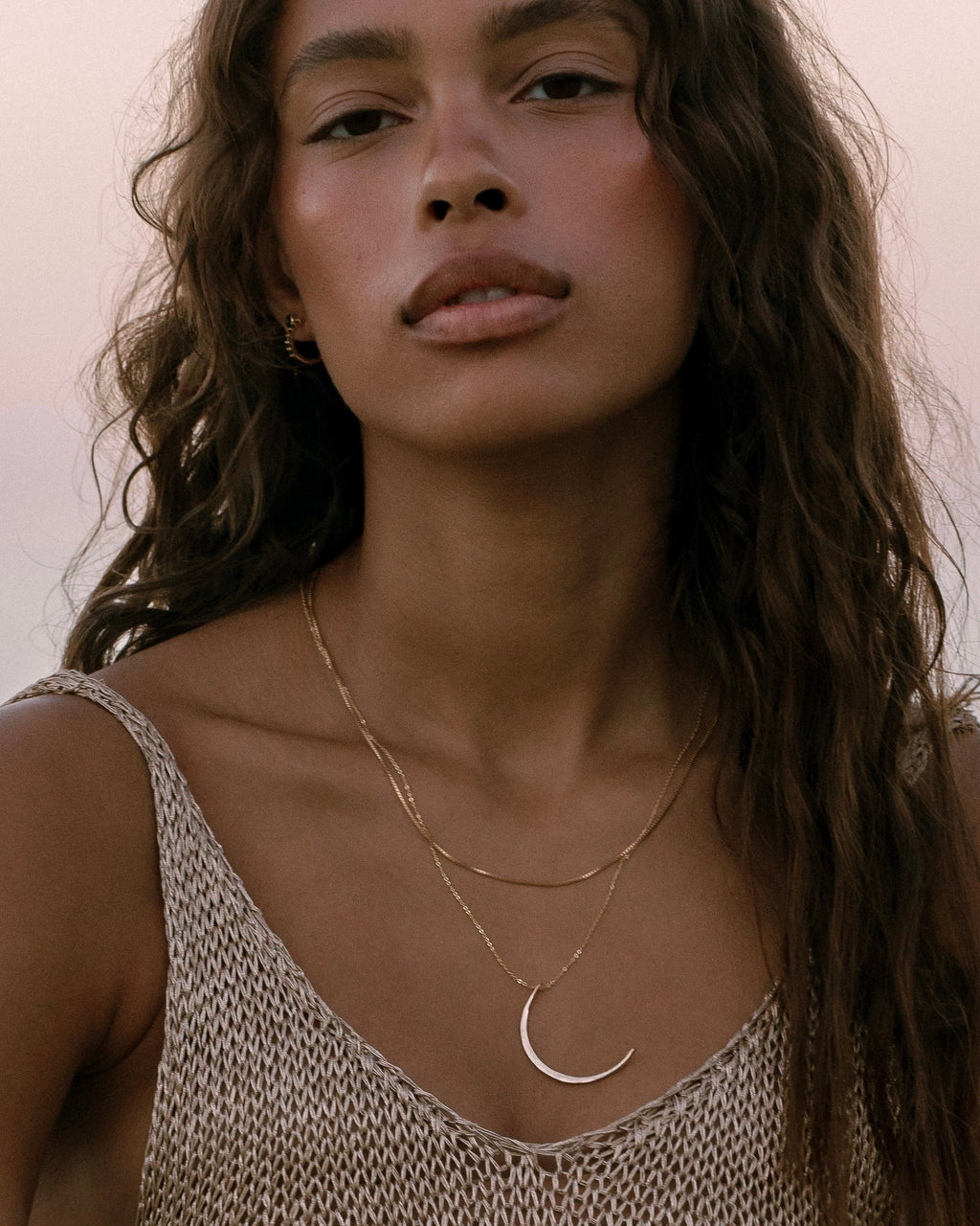 Model wearing layered gold necklaces with crescent moon pendant