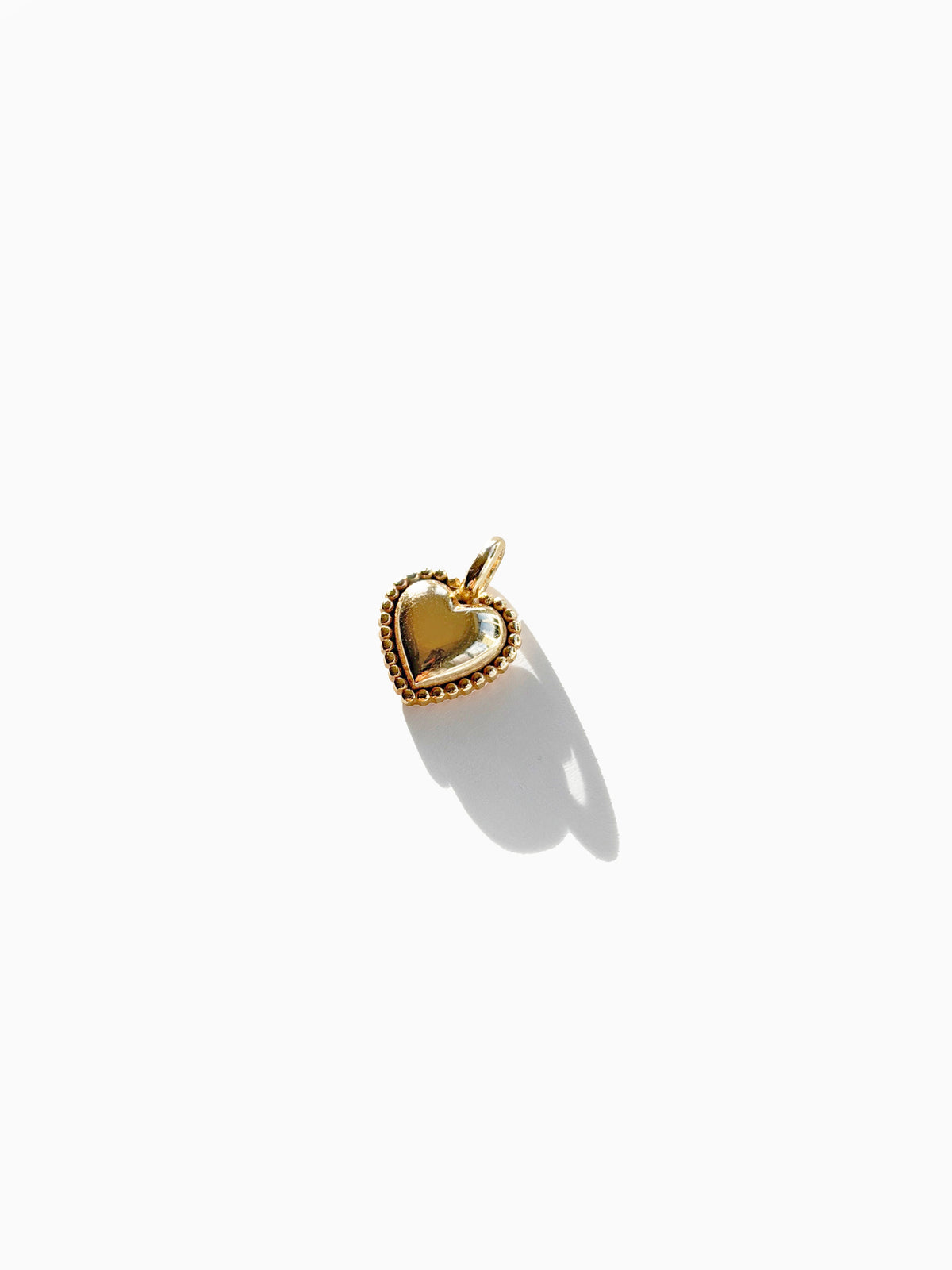 The LLUME Jewelry Build a Charm Necklace features a small gold heart-shaped pendant with a beaded border, ideal for customizing your jewelry collection and perfect as a charm on any necklace.