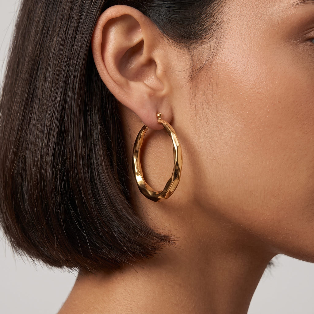 Woman with a dark bob wearing the Aire large faceted gold hoop earring