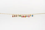 The Build a Birthstone Necklace by LLUME Jewelry features a gold chain with eleven unique, gold-plated gemstone charms in different shapes and settings, showcased against a plain white background.