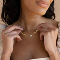 A woman holds the Mellow Name Heart Necklace, featuring the names Matthew and Sophia separated by a small diamond heart charm on a delicate chain.