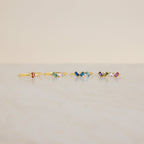 Five Cluster Baguette Birthstone Rings with colorful gemstones are arranged in a row on a light marble surface against a beige background, perfect as birthstone or personalized statement rings.