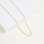 Close-up of the Figaro necklace laid over a white speckled tile surface, highlighting the alternating link pattern.
