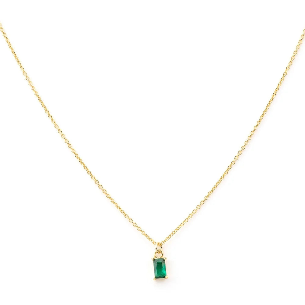 The Kismet Necklace features a simple and elegant gold-plated chain with a small, rectangular emerald green charm pendant set in gold, beautifully centered on the delicate chain.
