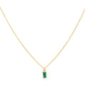 The Kismet Necklace features a simple and elegant gold-plated chain with a small, rectangular emerald green charm pendant set in gold, beautifully centered on the delicate chain.