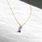 The Celia Necklace by LLUME Jewelry is a delicate gold vermeil piece featuring a small rectangular lilac gemstone pendant, displayed on a white textured surface in natural light.
