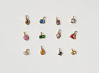 Twelve small, gold-plated charms by LLUME Jewelry are arranged in a row on white, perfect for creating your own Build a Birthstone Necklace.