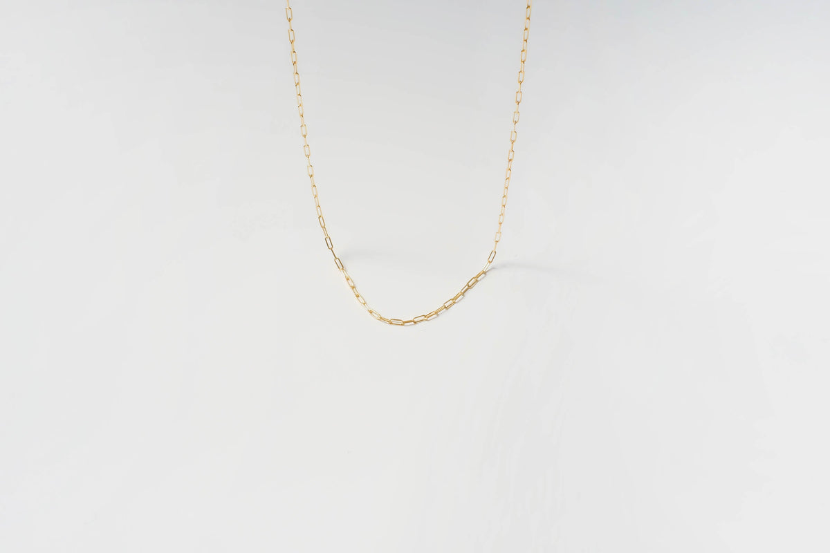 The Adelene Paperclip Chain by LLUME Jewelry features delicate gold-plated oval links, elegantly displayed against a plain white background.
