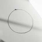 The Colette Necklace Silver by LLUME Jewelry, crafted from sterling silver, is arranged in an oval on a smooth, light surface with soft shadows—a versatile and elegant accessory.